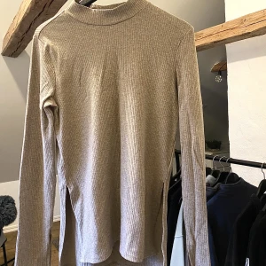 Långärmad tröja - Tröja från Nelly, ej använd.  Har slit på båda armarna samt vid sidan av tröjan (se bild) 