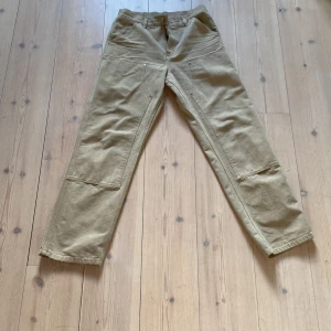 Carhartt carpenter pants - Beiga Carhartt carpenter pants, köpta på NK för 1600kr o använda Max 3 ggr, i nyskick. Dåligt ljus på bilderna, skriv för mer bilder!
