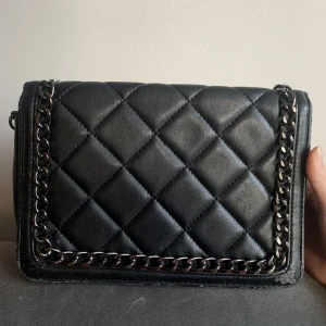 Svart väska - Säljer denna jättefina väska från asos då den inte kommer till användning längre!💕Den är väl använd (därav priset) och har några defekter i hörnet och på undersidan. Nypris: ca 200kr