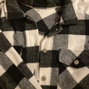 Kappa - Tror det heter kappa, som är rutig och helt oanvänd då det inte är min stil. Svart,vit,grå storlek S men kommer nog passa Xs och M lika bra