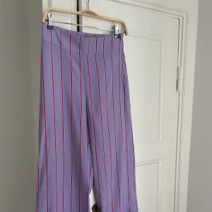 Vida byxor - Vida byxor från Lindex i storlek 34. Dom är lila/rosa randig och nästan aldrig använda. Byxorna är vida och lite för långa på mig som är 165 cm :)