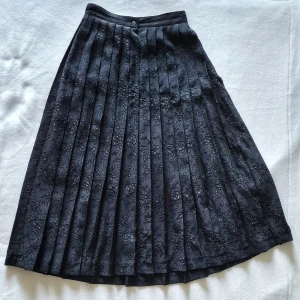 Veckad midikjol med rosor - Vintage kjol. Veckad gjord i creppat tyg med präglat rosmönster! Midilängd.   Daniel D. Paris, gjord i frankrike. 100% polyester.  Stl 40 enligt lappen men skulle säga att det är en S  Toppenskick, men för liten för mig.