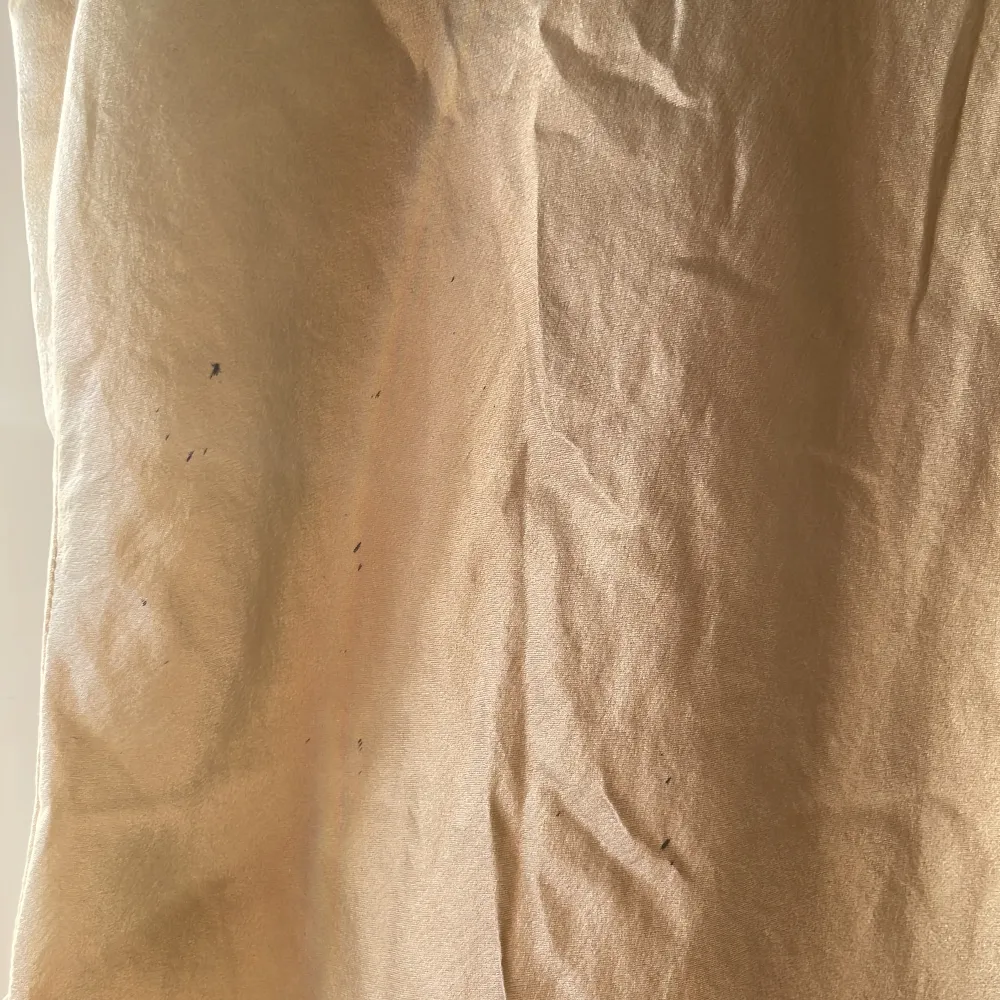 Krämvit sidenliknande linne med knytning på ryggen. En liten defekt på ryggen som visat i bild 3 . Blusar.