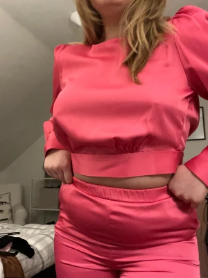 Satin sett - Rosa satin sett från Vero Moda. Prislapp sitter kvar på toppen (379,95kr) och byxorna är använda typ en gång. Blusen är öppen i ryggen och en rosett baktill. Byxorna är det resår i midjan och med fickor. Hela setet- 400 annars topp-250 byxor-200
