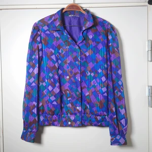 Vintageblus - Lila vintageblus i lite sidenlikt material. Resår i nederkant och dubbel knäppning. Ärmarna är lite transparanta🌿