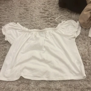 Topp  - En söt vit topp från Gina. Storlek M. Har en minimal röd fläck på bröstet men såpass liten så den knappt är märkbar. Fint skick. Kan postas men då står köparen för frakten!