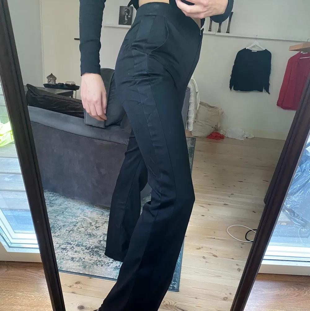Svarta kostymbyxor med ”detalj-rand” längst benet. Hög midja, snygga och stilrena, använt 2-3 gånger. Köpta för ca 1000 kr. Jeans & Byxor.