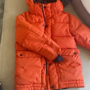 Everest jacka storlek 134 - En orange vinterjacka i storlek 134,lite trasig i sidan av armen men sydd.