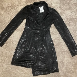 H&M glitter blazer klänning XS - Säljer denna glittriga blazer klänningen från h&m. Helt oanvänd och prislappen är fortfarande kvar. 😊Helt slutsåld. Det är storlek XS. Säljer pga köpte för liten storlek.🤗Ps klicka inte på köp nu!! Skriv först och ni står för frakten (29-39kr)🤗