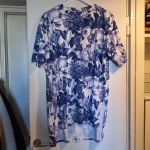 Oversized t-shirtklänning - Oversized t-shirtklänning köpt på Monki. Vit med blå blommor.  Ej mycket använd. 