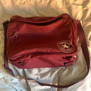 converse axelremsväska  - jätte rymlig axelremsväska från converse, den får plats med typ 5 datorer och halva din garderob. den har lite fläckar som går att ta bort men på sista bilden visar jag en fläck som inte går bort. den har många olika fickor så du kan ha me den på resor