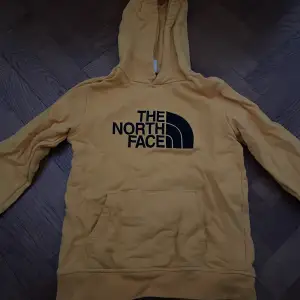 Fin gul North Face hoodie. Säljer billigt pga hål vid högra sidan av magfickan, ingenting som inte går att laga💛