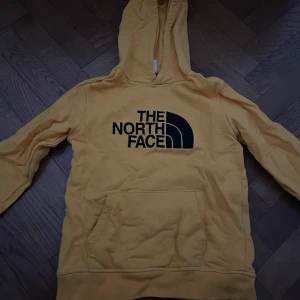 The north face  - Fin gul North Face hoodie. Säljer billigt pga hål vid högra sidan av magfickan, ingenting som inte går att laga💛