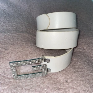 Skärp - Ljusrosa/beige skärp med rhinestonemärke där fram. 