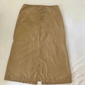 Ljusbrun mocka midi kjol  - Midi kjol i storlek 46 från Lindex i mocka imitation. Midjemått på 86cm och 88cm lång.100% polyester och tål därför tvättmaskin istället för kemtvätt. I gott skick utan tecken på användning. Dma gärna vid frågor eller funderingar! Köparen står för frakt. 