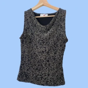 Linne - Glittrigt linne med blommönster cowlneck. Uppskattad storlek m. Färg: svart och silverglitter  Material: 83% polyamide, 11% polyester, 6% elastan. Mycket stretch. Om du har några frågor eller vill se mer bilder är det bara att skicka iväg ett meddelande:)