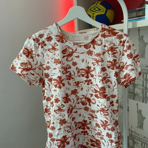Blommig röd t-shirt stl S - En somrig och ganska tunn t-shirt som är perfekt för lite varmare väder. Är i bra skick. Märket är The Tailorino Club.
