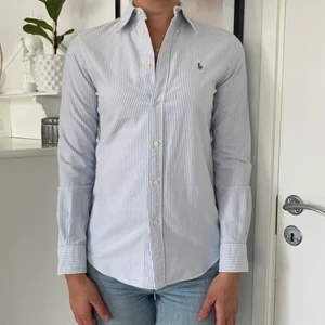 Skjorta från Ralph Lauren - Blå/vit randig skjorta från Ralph lauren köpt i USA. Figursydd modell (custom fit). Storleken är S och jag är 178 cm lång. Väldigt fint skicka. Storleken är S/P och jag är 178cm lång 