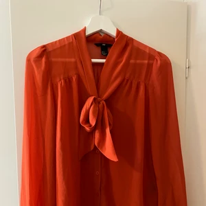 En orange blus från H&M - En orange men genomskinlig blus från H&M, den är väldigt fin men behöver stödjas av åtminstone ett vitt linne under.