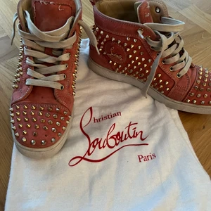 Christian Louboutin skor  - Ett par rosa Christian Louboutin sneakers med nitar. Bra skick utom en bit som åkt av som syns på andra bilden. Går lätt att hitta en ny i butik 
