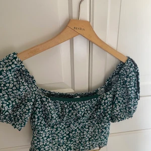 Grön topp - Mörkgrön topp med vita blommor, i bra skick från hm. 