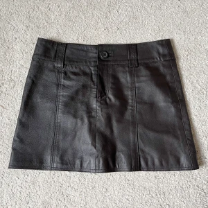 Mörkbrun Läderkjol - Säljer denna mörkbruna kjol i äkta läder! Storleken är M, 80cm midja och 37cm lång❤️Frakten är inte 66kr utan 57kr🫶