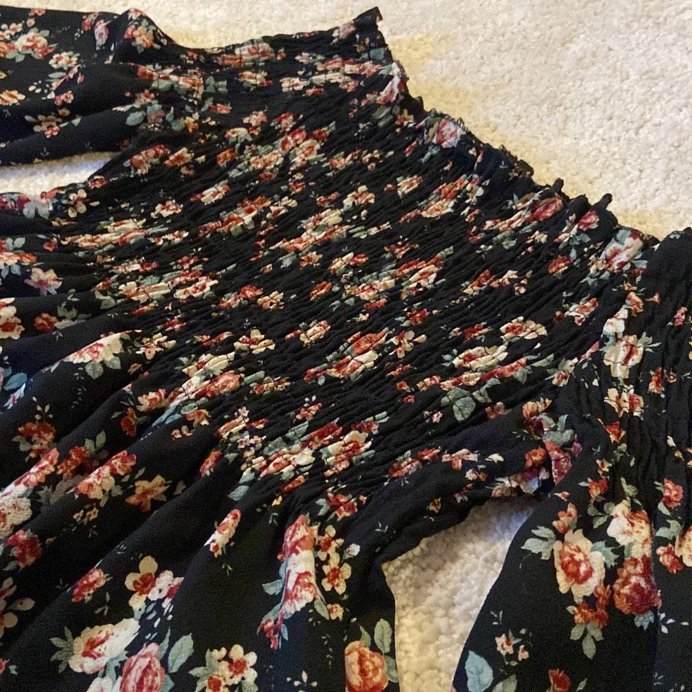 Offshoulder blus i blommigt tyg, smockat runt brösten för de som behöver extra plats. Använd någon enstaka gång . Puserot.