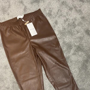 Bruna skinnbyxor  - Ett par bruna skinnbyxor i stolek L, nyskick med prislappen kvar.