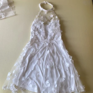 Vit vacker klänning - Vit klänning med blomdetaljer, knä längd. Använd 1 gång.