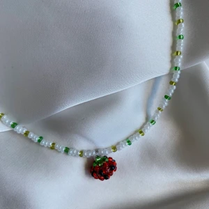 Pärlhalsband med smultron  - Supergulligt och unikt pärlhalsband med smultronberlock! 🍓 Så fint nu på sommaren!! Både halsbandet och berlocken är handgjorda av oss. Frakt 13kr om du betalar med Swish 🥰