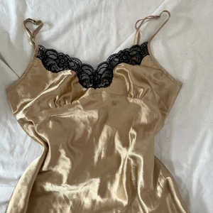 Guldigt nattlinne - Drömmigt nattlinne i ett guldigt sidentyg med svarta spetsdetaljer. Visas på mig som bär S i toppar och M/L i byxor. Köpare står för 26kr frakt med frimärken eller 51kr spårbar frakt. 