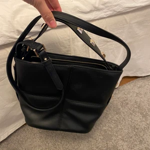 Zara väska - Svart väska med nitar på. Går att ha som crossbody och även att bära i det lilla handtaget. Knappt använd, nyskick