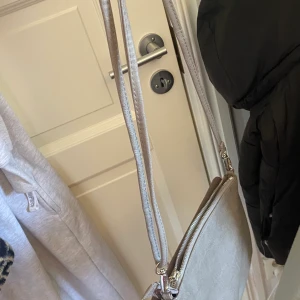 Väska - Säljer även den a fina väska som är i olika nyanser av grå med silvriga detaljer, den har två olika fack en med dragkedja och en med magnet knapp, ps: det går att skustera banden
