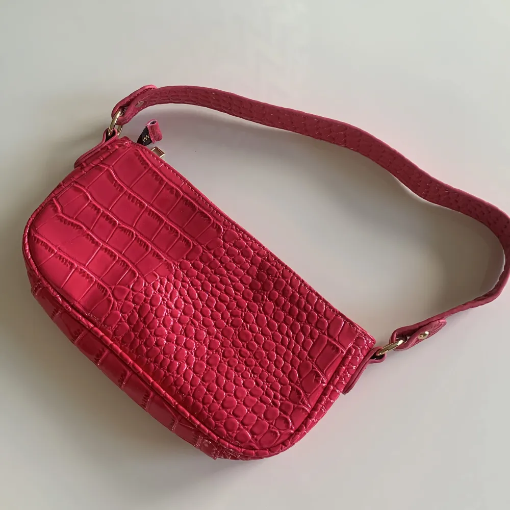 Ceriserosa väska med ”baguette”/”krokodil”-mönster. Ser röd ut på bilden men är 100% mörkrosa i verkligheten.. Väskor.