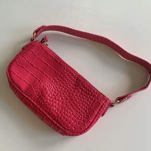 Ceriserosa väska med ”baguette”/”krokodil”-mönster. Ser röd ut på bilden men är 100% mörkrosa i verkligheten.