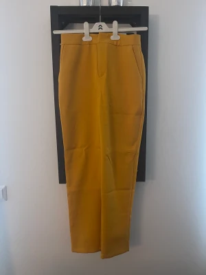 Kostymbyxor från NA-KD - Helt oanvända kostymbyxor från NA-KD. Senapsgula med två fickor fram. Köparen betalar frakt. 