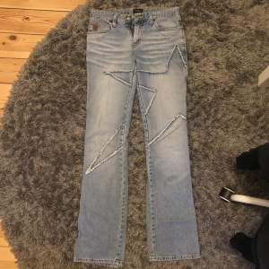 Ljusblå jeans från crocker med en stjärna på benet, lite slitna med lös knapp men sjukt coola ändå! Frakt tillkommer på 63kr midjemått: 72cm Innerbenslängd: 85cm 