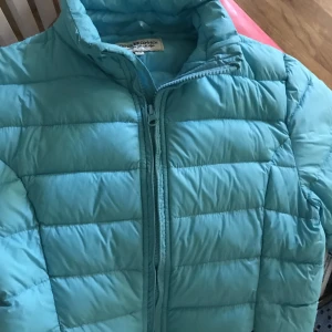 Lättvikts jacka  - Tunn, mjuk, lätt men ändå varm och skön jacka som kan vikas ihop till mycket liten i packningen. Turkos, obetydligt använd, mycket fin och passar både till tjej och kille. Storlek 146 kan jämföras med en XS eller S. 