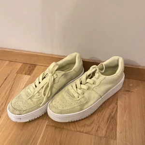 Neon gul/gröna skor - Skor i neon gul/grön färg med hög sula. Sparsamt använda med en del smutsfläckar men inga defekter utöver det. 