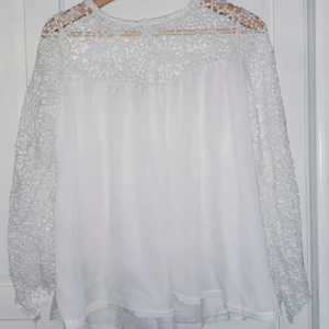 Flowig vit topp med ärmar i spets - Vit topp med ärmar i spets som inte kommer till användning. Osäker på storlek och märke då det inte står meb skulle säga ca M men passar nog S också. Knäppning i nacken med knappar.