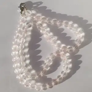 Halsband gjort med rosa/genomskinliga plast pärlor med klämma i metall.