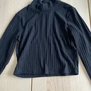 En fin svart långärmad tröja med en högre krage. I storlek s men känns och ser ut som en xs