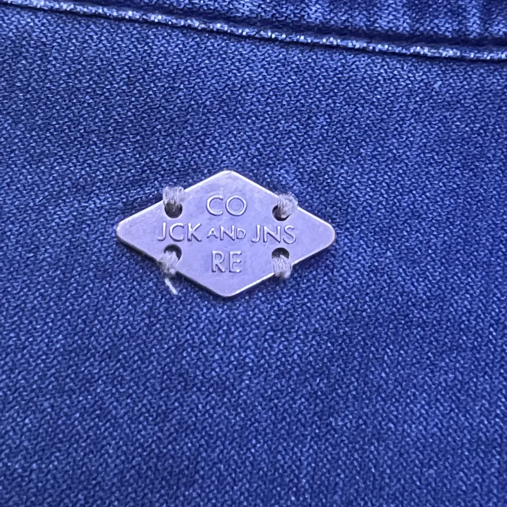jeans skjorta från jack and jones en knapp är sönder men det sitter en extra knapp på lappen längst ner på skjortan. Skjortor.