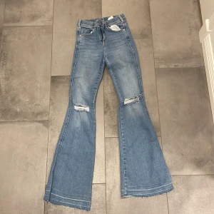 Flare jeans  - Jättefina, blåa, flare jeans med hål säljs nu i bra skick. Dom är inte slitna men sömmarna vid fötterna på byxorna är sprättade så att dom ska bli längre. Jättefina ändå och är köpta på denim rebel.