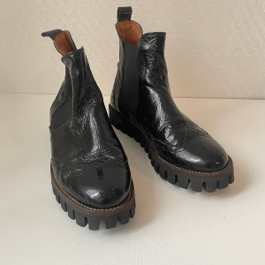 Ganni boots - Lackade Chelsea boots, sulan har lossnat lite men går att limma. Annars i väldigt bra skick