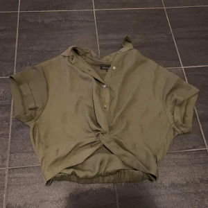 Knuten skjorta - Armegrön "knuten" skjorta. Använd en gång, nyskick. Köparen står för frakt. 