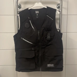 Väst - ”Tactical” väst med detaljer och många fickor. Oanvänd
