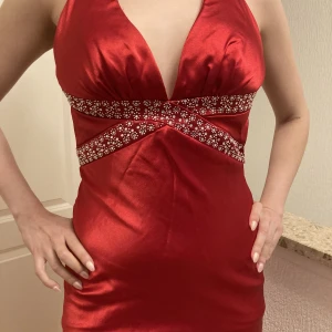 Röd långklänning i siden - Otroligt vacker och elegant klänning med naken rygg. Storlek 34 men kan även passa en 36a, vilket jag är på bilden.  Använd en gång och i mycket bra skick, behöver enbart strykas lite.  Originalpriset är 1700 kr. Skickar fler bilder vid intresse.