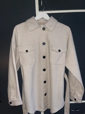 Oversized kappa från Nelly  - Kappa från NLY trend i storlek 32. Jackan är oversized så storlek 32 motsvarar mer en 36. Jackan är helt ny och endast testad. Färg: beige. Frakt tillkommer 😊
