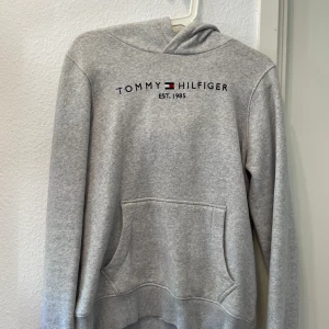 Tommy Hilfiger Hoodie - Jättemysig Tommy-hoodie i fint skick. Den är köpt på KidsBrandStore i storlek 164 och sitter perfekt på mig som brukar ha S. Perfekt att ha nu till sena sommarkvällar! Nypris: 699 kr Köparen står för frakt